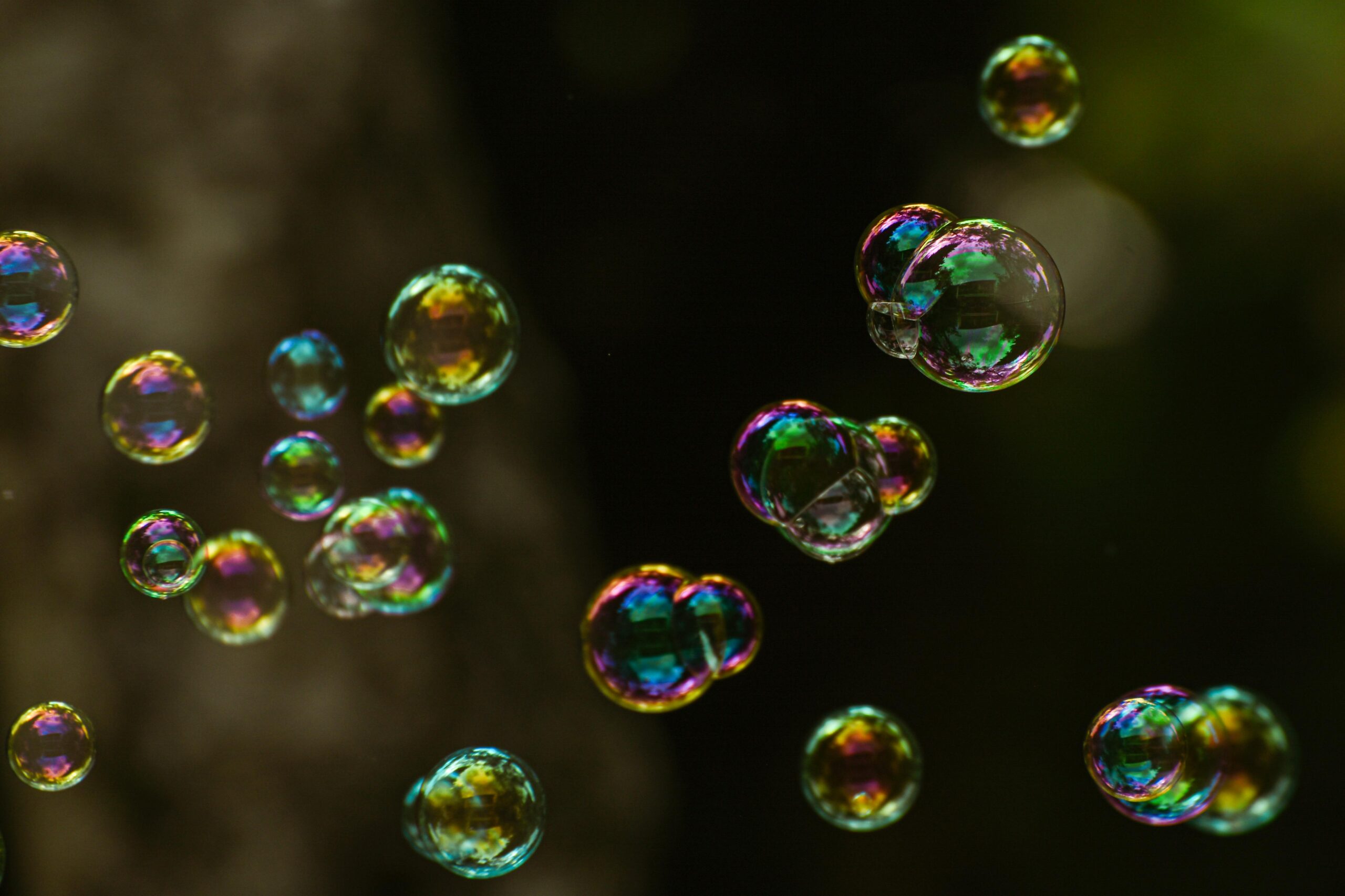 Close-up of iridescent soap bubbles against a dark, blurred background.