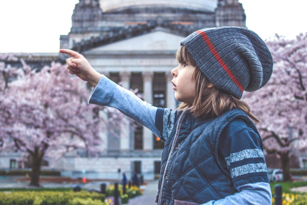 pexels-photo-415242-415242 A young girl in a beanie points towards cherry blossoms in front of a historic building.