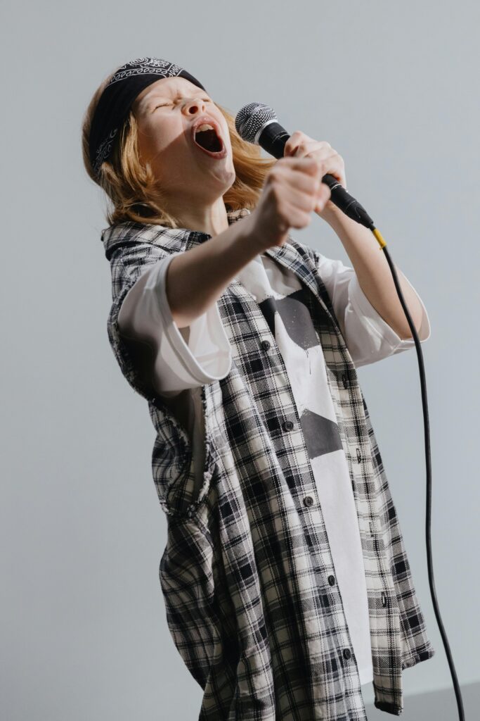 pexels-photo-9643908-9643908 Young girl passionately singing into microphone, expressing excitement.